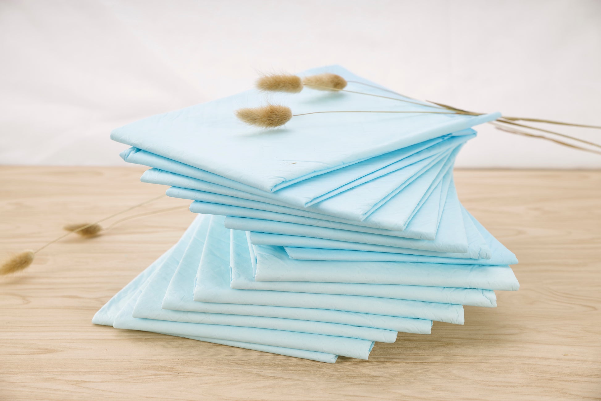 Light blue underpads stack on wood, multiple folded pads